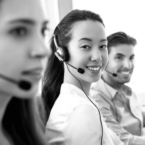 Smiling beautiful Asian woman working in call center office with international team as the customer care operators